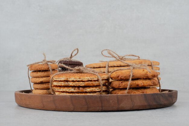 Pila de galletas atadas con cuerda sobre placa de madera.