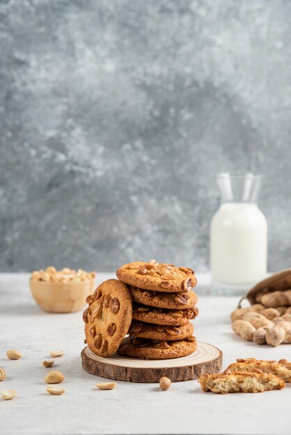 Pila de galletas, cacahuetes y leche fresca en la mesa de mármol.