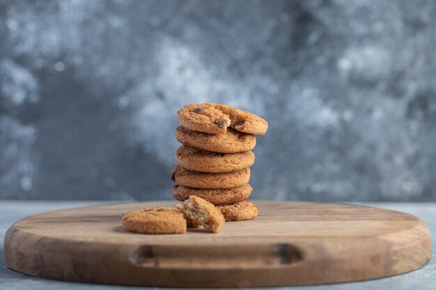 Pila de galletas con chispas de chocolate sobre tabla de madera.