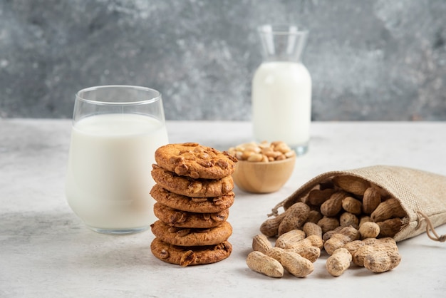 Pila de galletas con miel, leche y cacahuetes sobre mesa de mármol.