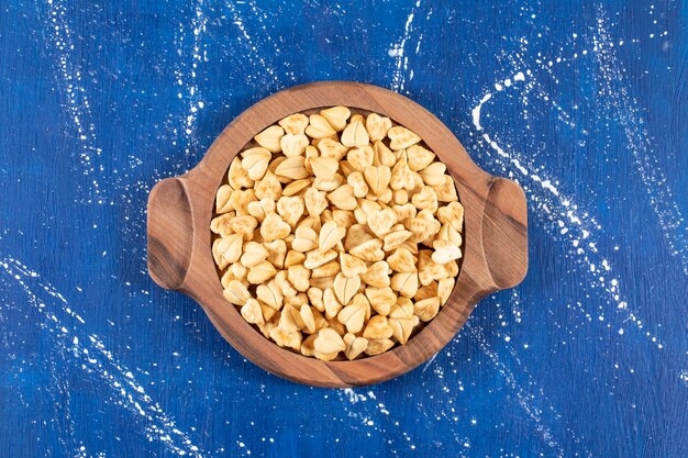 Pila de galletas saladas en forma de corazón colocadas sobre una tabla de madera.