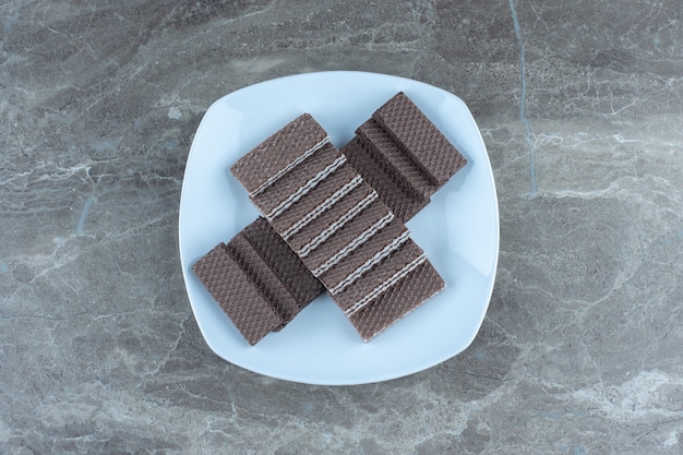 Pila de gofres de chocolate en un plato de cerámica blanca.