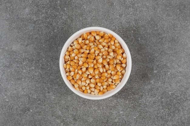 Pila de granos de maíz crudo en un tazón blanco.