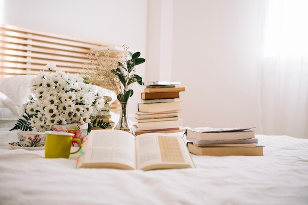Pila de libros y flores en la cama