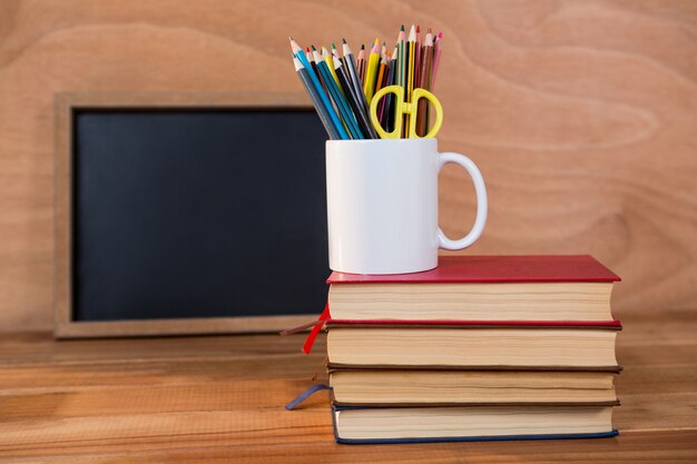 Pila de libros con lápiz de color en una taza