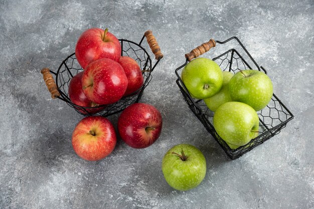 Pila de manzanas verdes y rojas frescas colocadas en cestas metálicas.