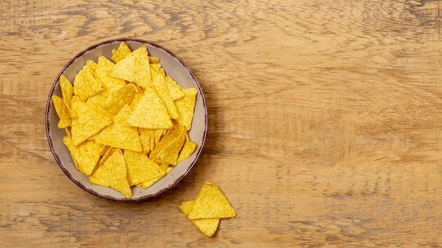 Pila de nachos en plato sobre mesa de madera