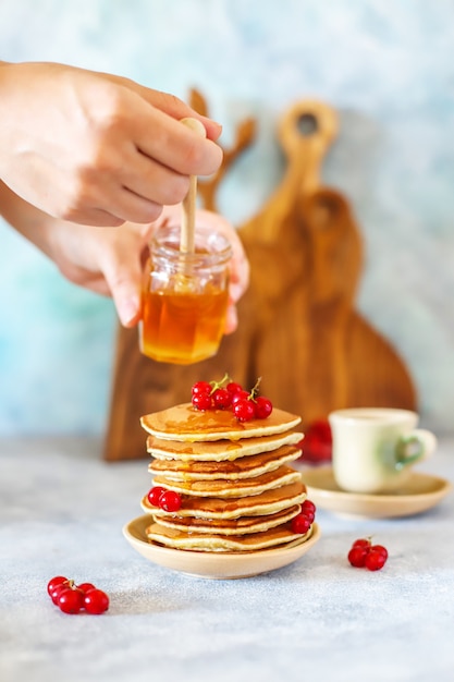 Foto gratuita pila de panqueques caseros con miel y bayas.