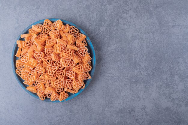 Pila de pasta en forma de corazón en placa azul.