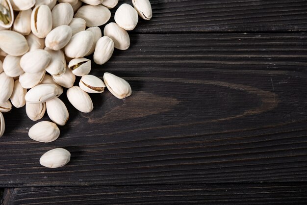 Pila de pistachos en el primer plano de la cáscara sobre una mesa de madera. Enfoque selectivo