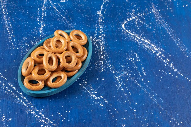Pila de pretzels redondos salados colocados en placa azul.