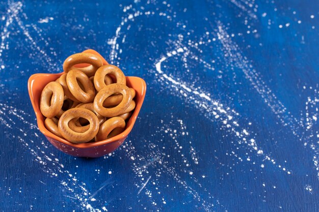 Pila de pretzels redondos salados colocados en un tazón de naranja