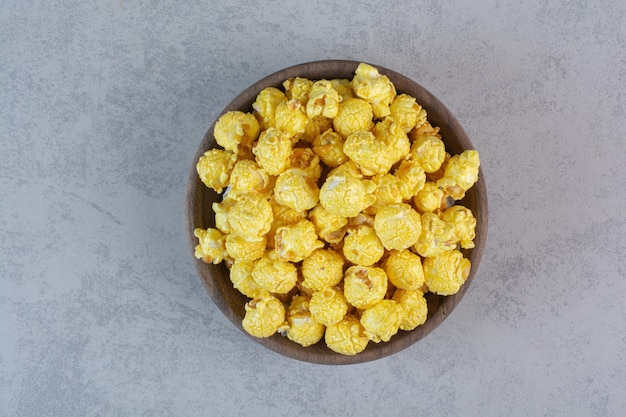 Pila recubierta de caramelo amarillo de palomitas de maíz en mármol.