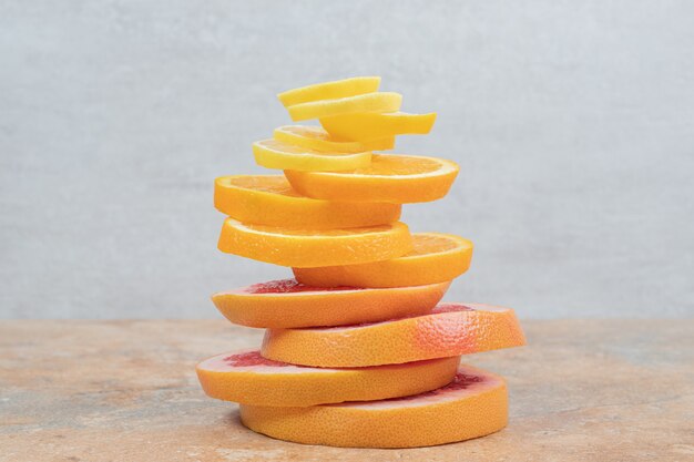 Pila de rodajas de limón, naranja y pomelo en la mesa de mármol. Foto de alta calidad