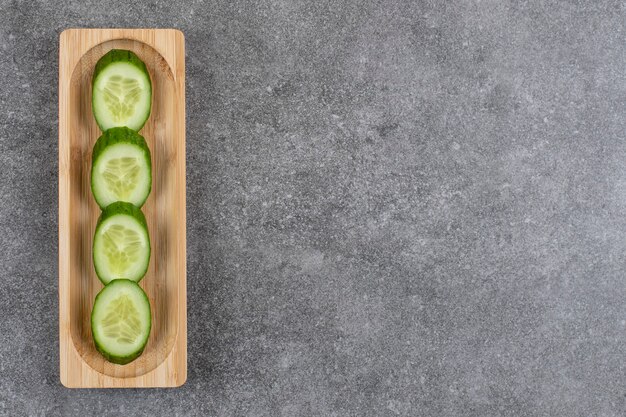 Pila de rodajas de pepino fresco sobre tabla de madera.