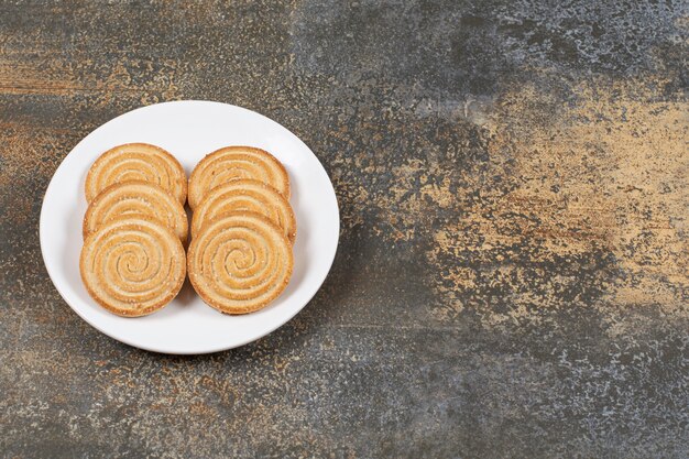 Pila de sabrosas galletas redondas en un plato blanco.