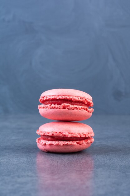 Pila de sabrosos macarons rosados colocados sobre superficie gris