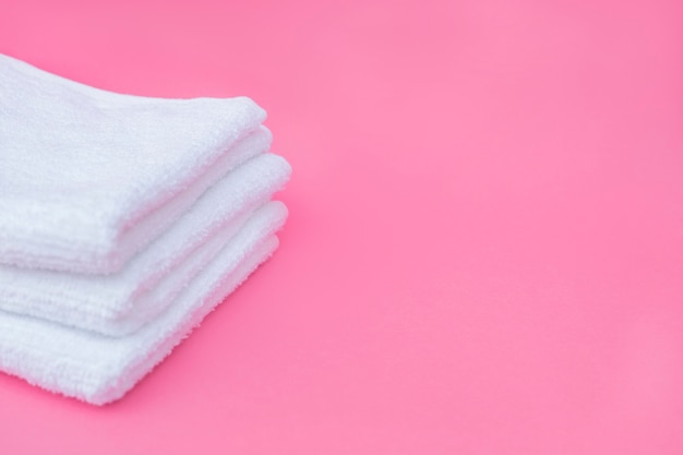 Pila de toallas blancas sobre fondo rosa