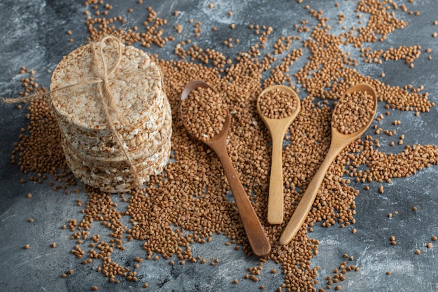 Pila de tortas de arroz y trigo sarraceno crudo sobre superficie de mármol