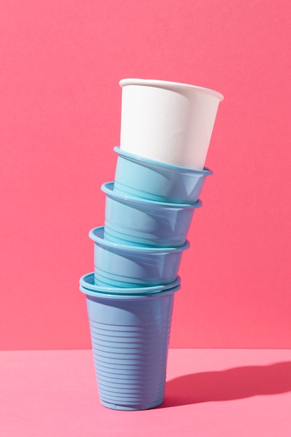 Pila de vasos de plástico azul y vaso de papel blanco