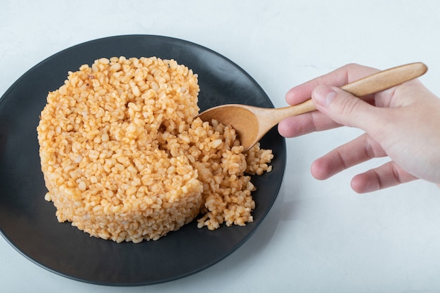 Pilaf de bulgur delicioso en plato oscuro.