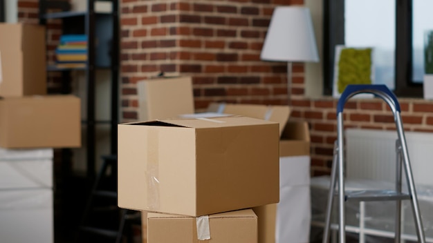 Pilas de cajas de cartón en propiedades inmobiliarias vacías con muebles, lámparas y decoración interior. Nadie en el apartamento de la sala de estar con contenedores de almacenamiento de cartón y paquetes de carga. De cerca.