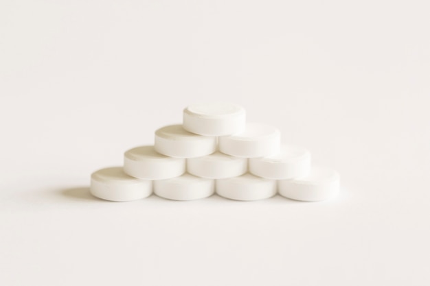 Píldoras blancas formando pirámide sobre el fondo blanco