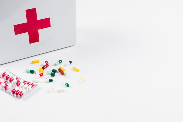 Foto gratuita píldoras coloridas con botiquín de primeros auxilios aislado en el contexto blanco
