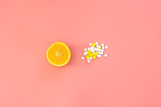 Píldoras dispersas sobre fondo rosa concepto de vitamina c naranja endecha plana