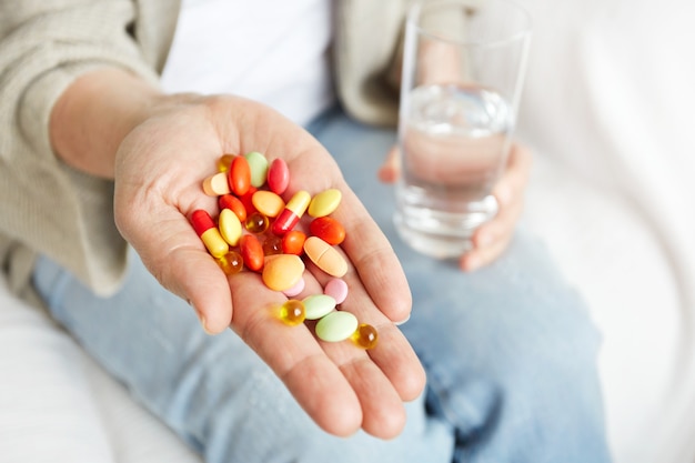Píldoras, tabletas, vitaminas y medicamentos se amontonan en manos maduras