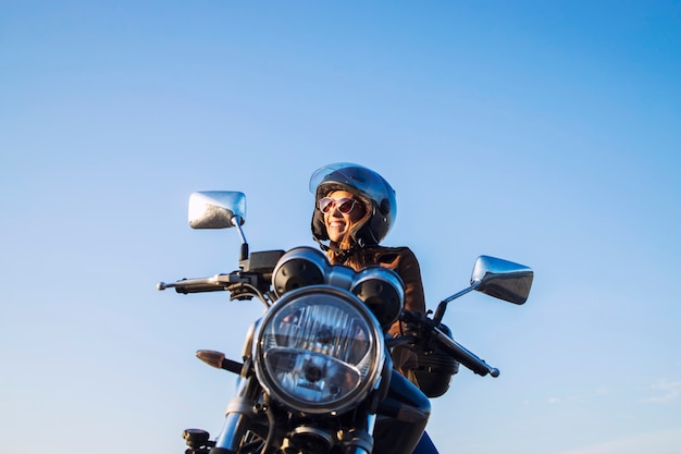 Piloto de moto femenino con casco y montando motocicleta de estilo retro