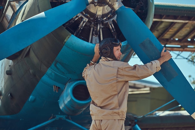 Piloto o mecánico en un equipo de vuelo completo comprueba la hélice de su avión militar retro antes del vuelo.