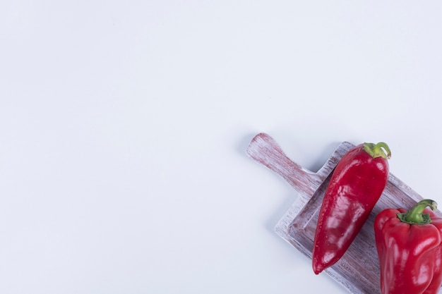 Pimentón rojo y pimiento en una esquina de la tabla de madera.