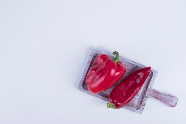 Pimentón rojo y pimiento sobre una tabla de madera.