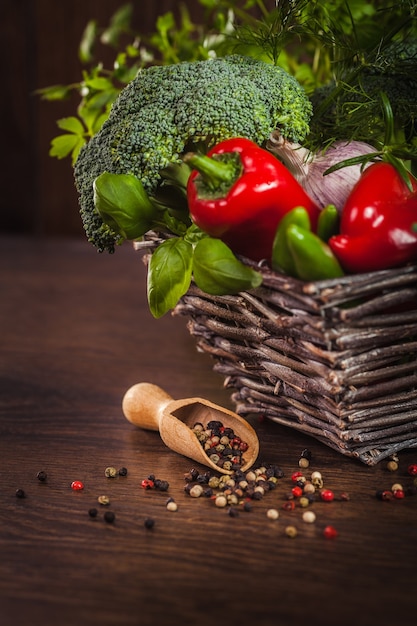 Pimienta sobre madera con verduras en canasta