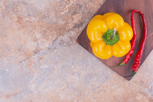 Foto gratuita pimiento amarillo con chiles rojos sobre una tabla de madera