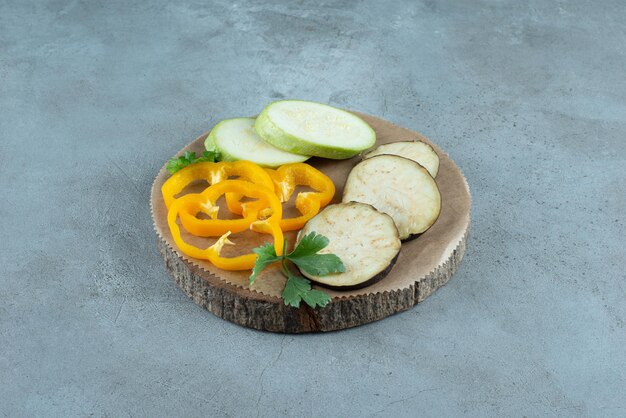 Foto gratuita pimiento, berenjena y calabacín en rodajas en pieza de madera.