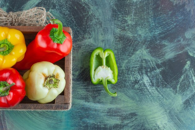 Pimiento surtido en una caja de madera, sobre el fondo de mármol.