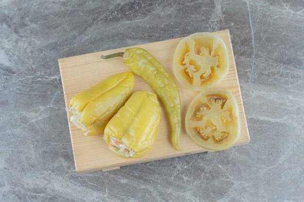 Pimiento verde relleno de chucrut y rodajas de tomate verde sobre tabla de madera.