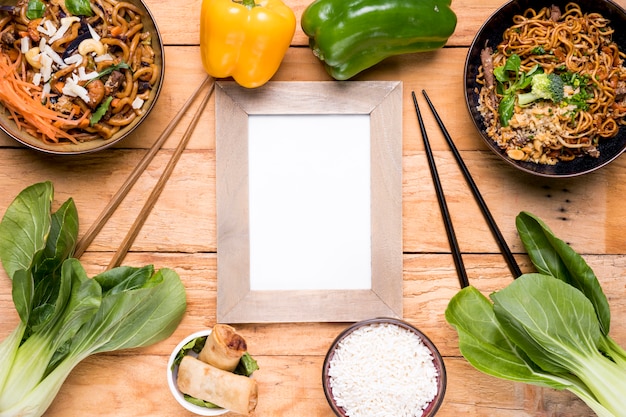 Pimientos; bokchoy palo de picar rollitos de primavera; Tazón de fideos de arroz y udon en el escritorio de madera