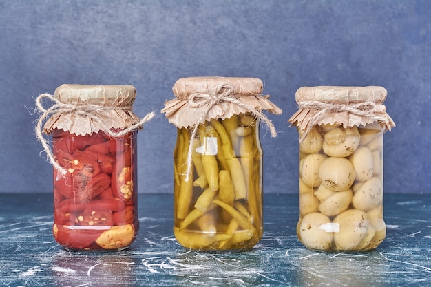 Pimientos y champiñones en escabeche en un frasco de vidrio en azul.