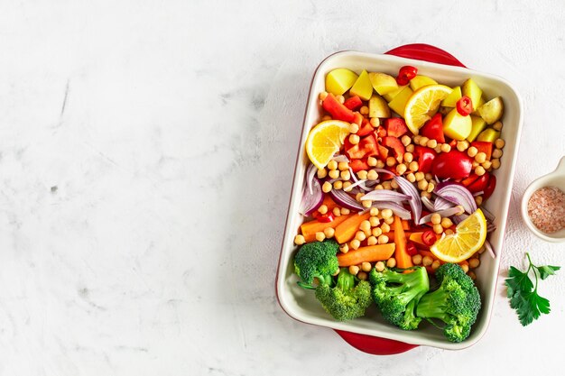 Foto gratuita pimientos crudos patatas brócoli garbanzos y cebollas con aceite y especias en un plato de horneado