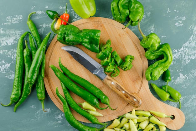 Pimientos con cuchillo sobre yeso y tabla de cortar,