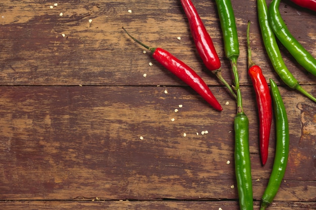 Pimientos jóvenes rojos y verdes colocados en un viejo tablón rojo