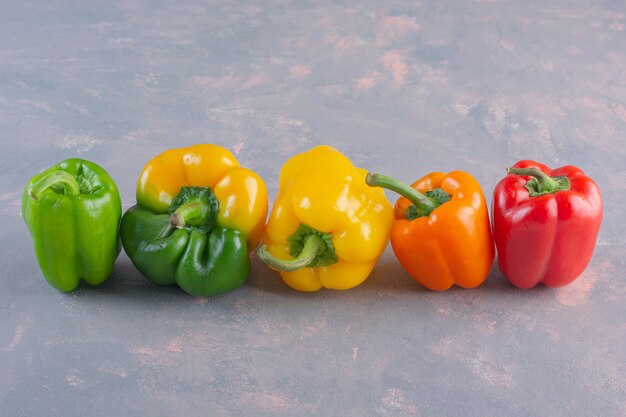 Pimientos orgánicos coloridos frescos colocados sobre fondo de piedra.