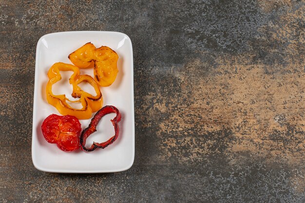 Pimientos a la parrilla en rodajas en un plato blanco.