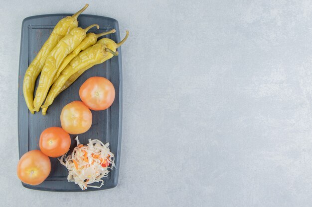 Pimientos picantes, tomates y chucrut en una tabla