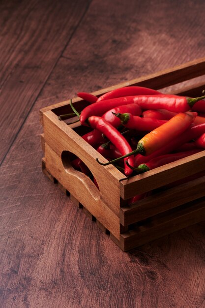 Pimientos rojos en una caja puesta sobre una superficie de madera