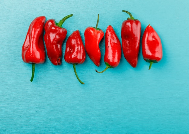 Pimientos rojos en la pared azul, vista superior.