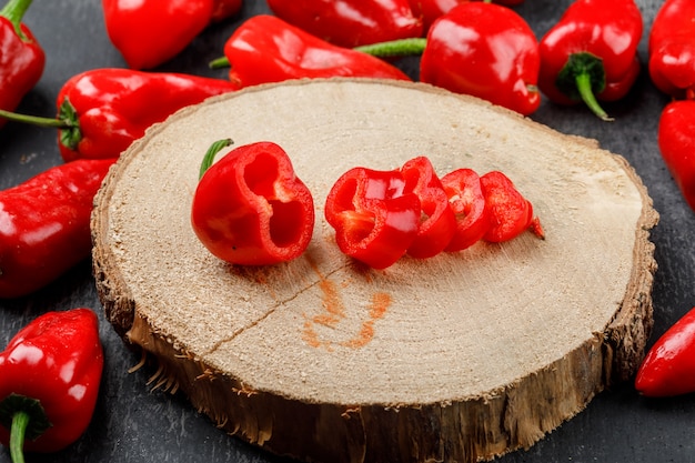 Pimientos rojos en una pieza de madera vista de ángulo alto en una pared gris sucio